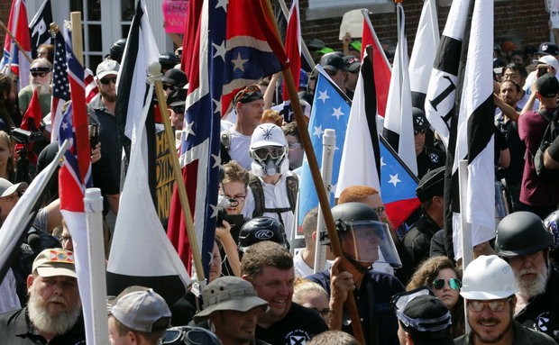 White nationalist demonstrators walk into the entrance of Lee Park surrounded by counter demonstrators in Charlottesville, Va., on Saturday, Aug. 12, 2017. (AP Photo/Steve Helber)